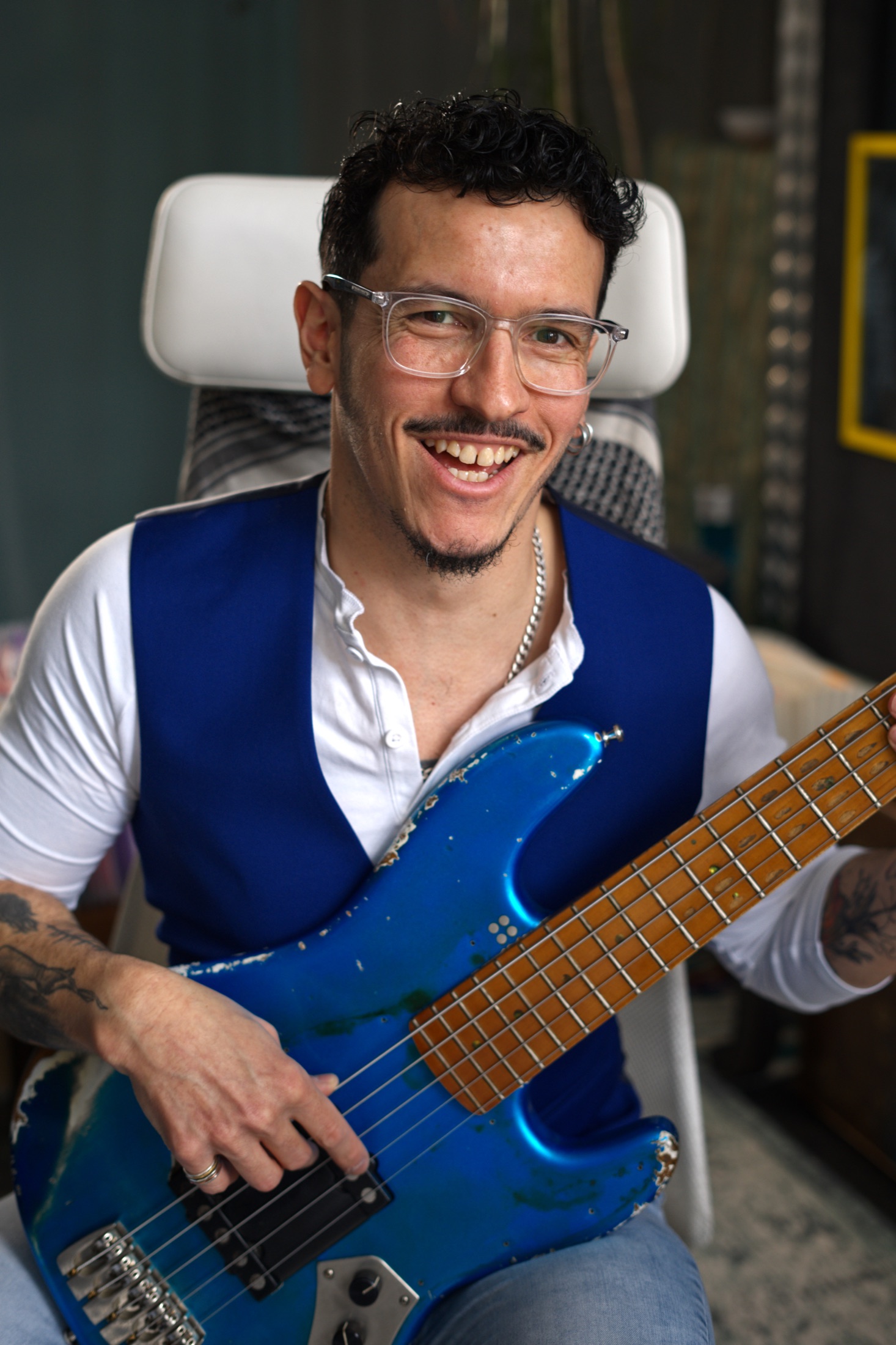 Edward smiling with a blue bass guitar in the studio